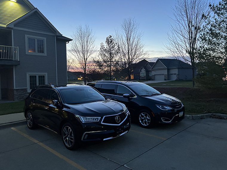 Two black cars parked in a parking lot