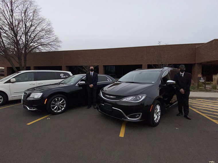 A group of men standing next to two cars