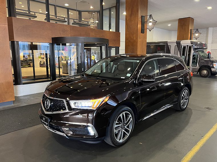 A black Acura MDX parked in front of a building